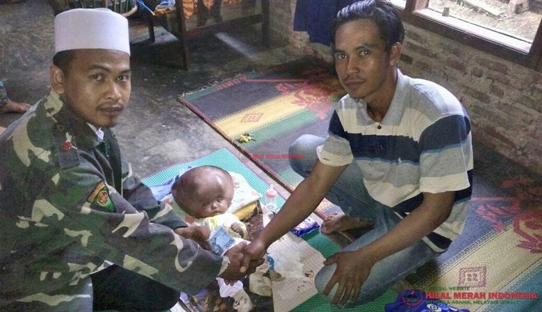 Agung (kiri) saat menyerahkan bantuan uang tunai kepada Adi Supriyanto (kanan).