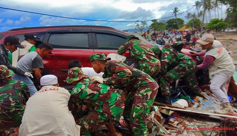 Relawan DPP HILMI-FPI bersama anggota TNI mengangkat dan mengevakuasi kendaraan yang menimpa reruntuhan bangunan